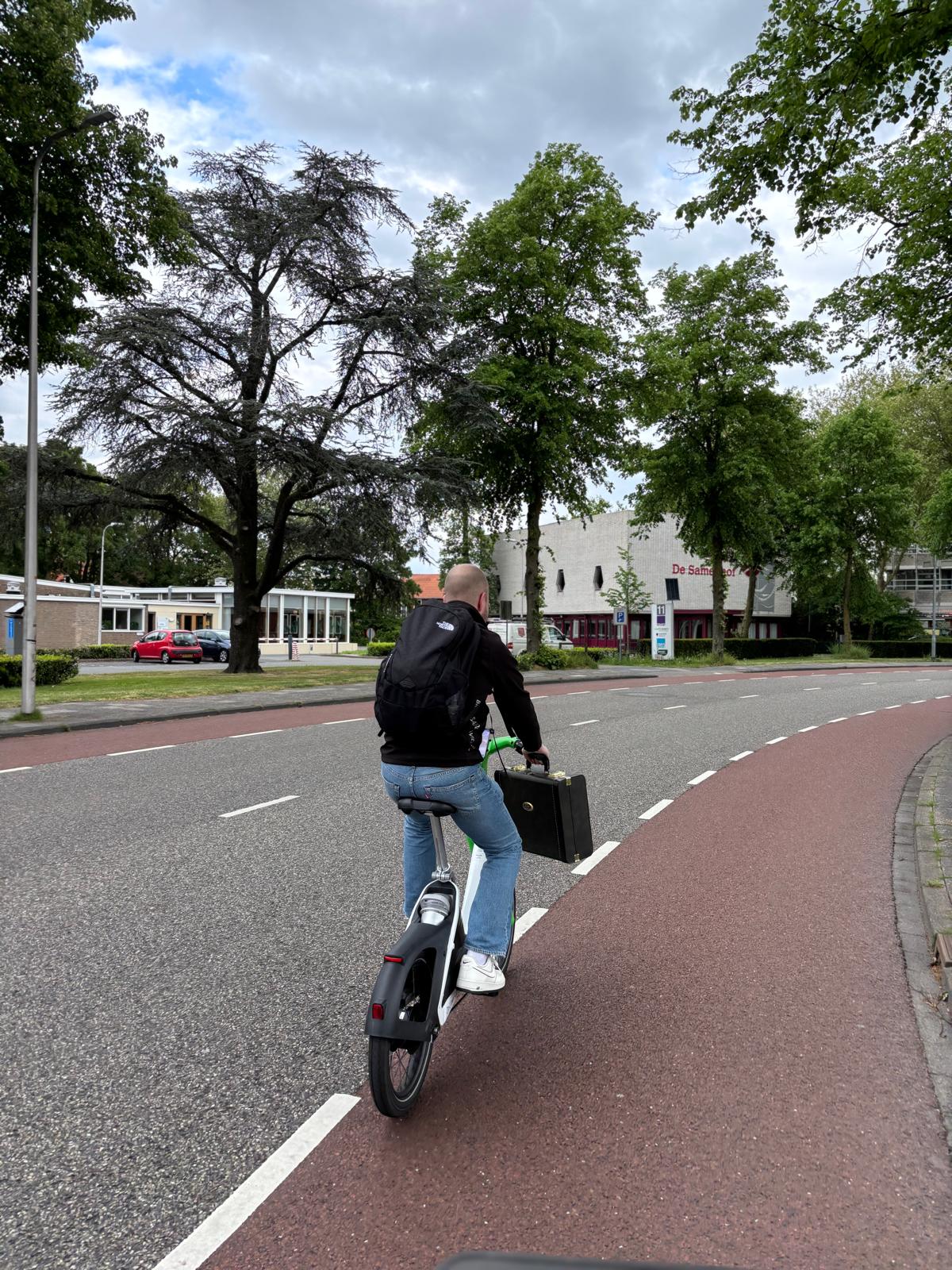 Iemand met een fiets op een landweg in het vlakke landschap